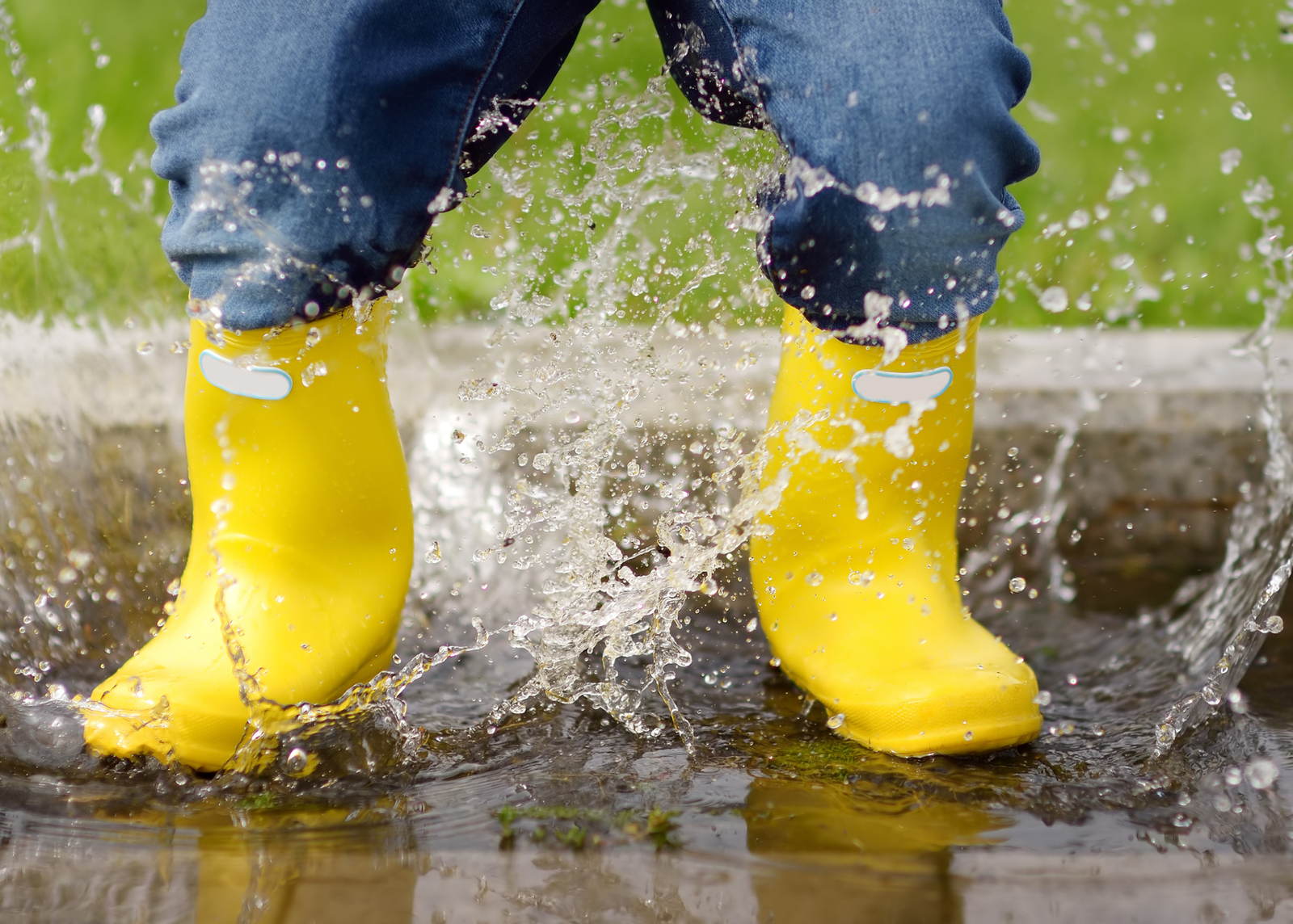 yellow gumboots splashing in puddle